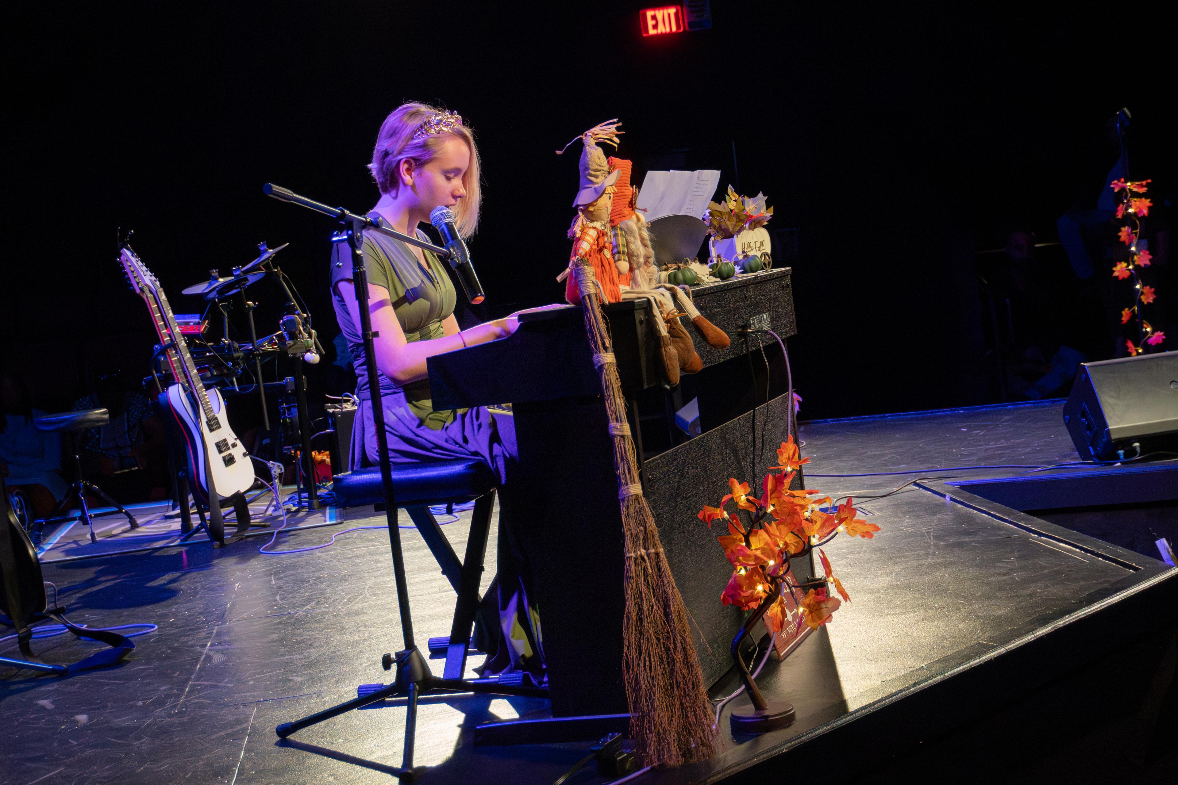 Student playing piano and singing at fall recital