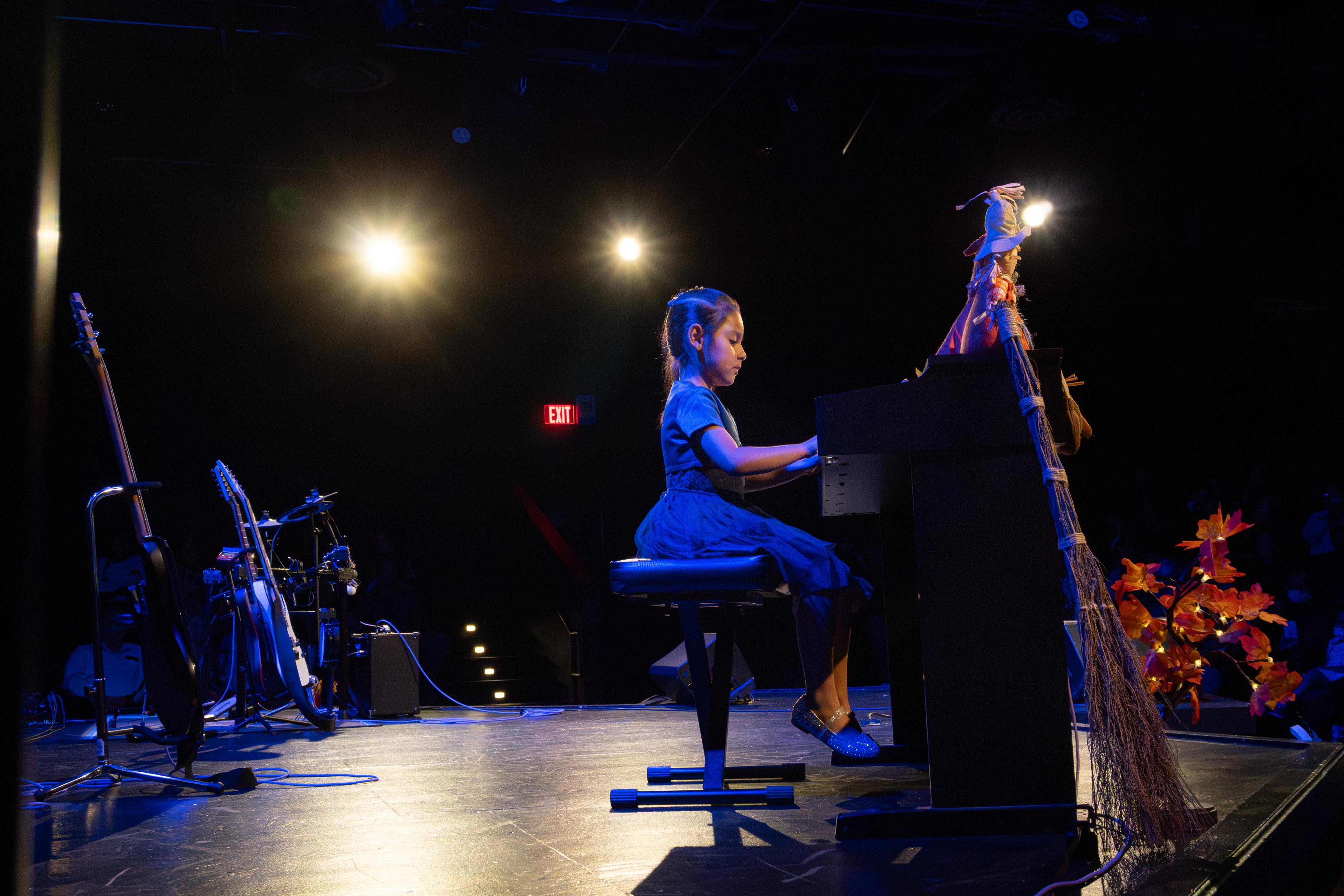 Young girl performing piano solo on stage at recital