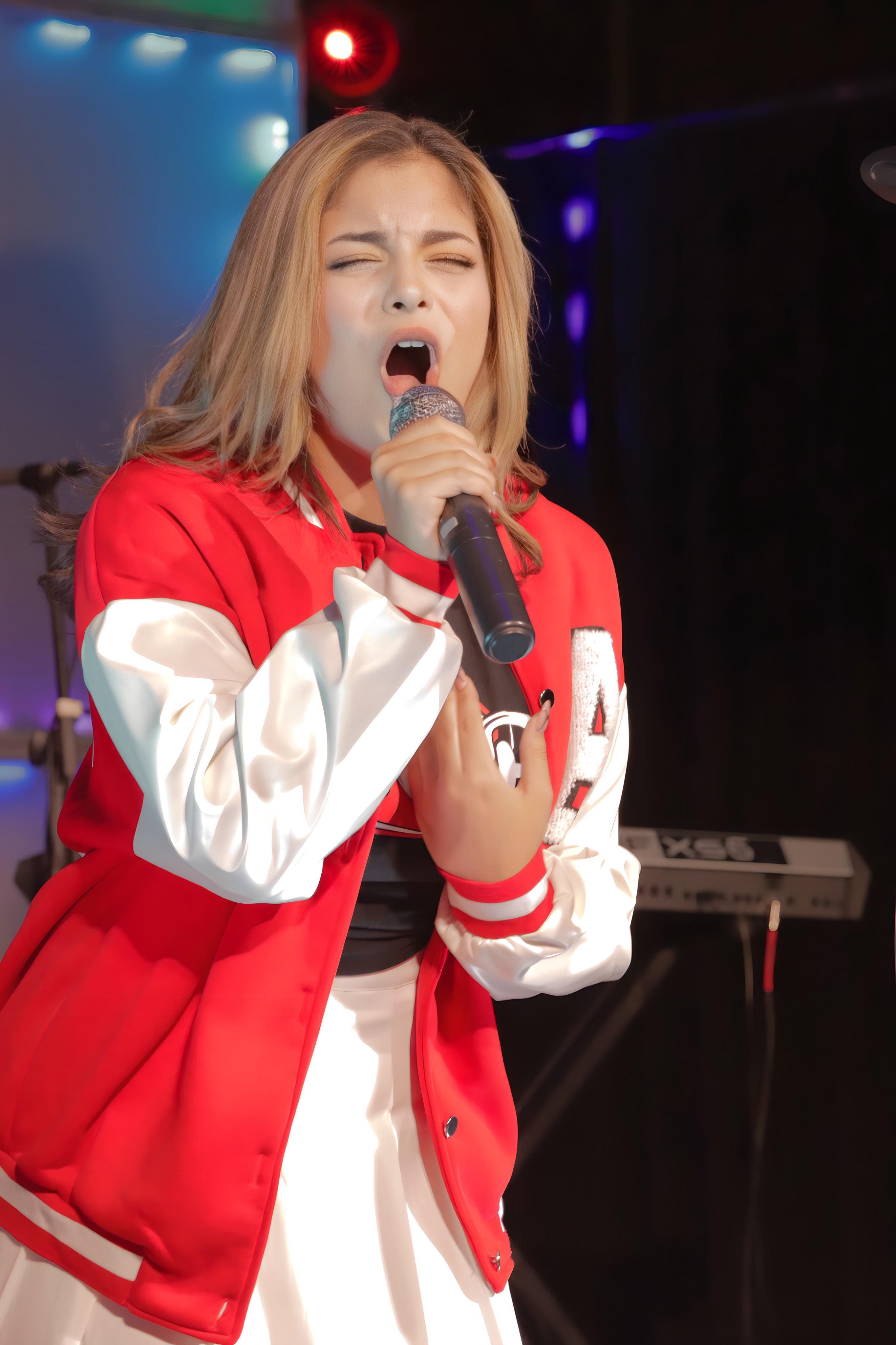 Vocal student performing in red jacket on stage